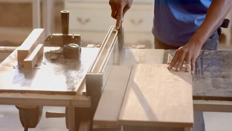 african american man using chisel on wooden board on shop workbench, with clamp handle, copy space