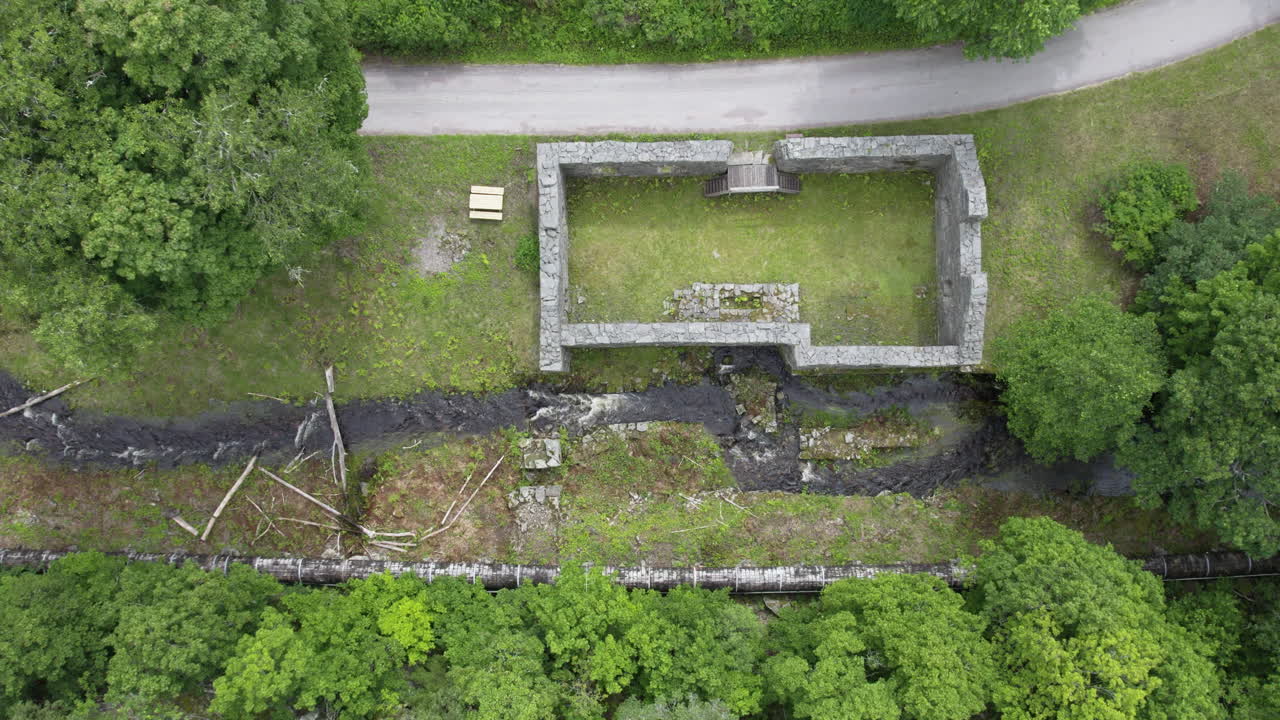 Ruins of Bäckefors bruk with a nearby stream and trees in the landscape
