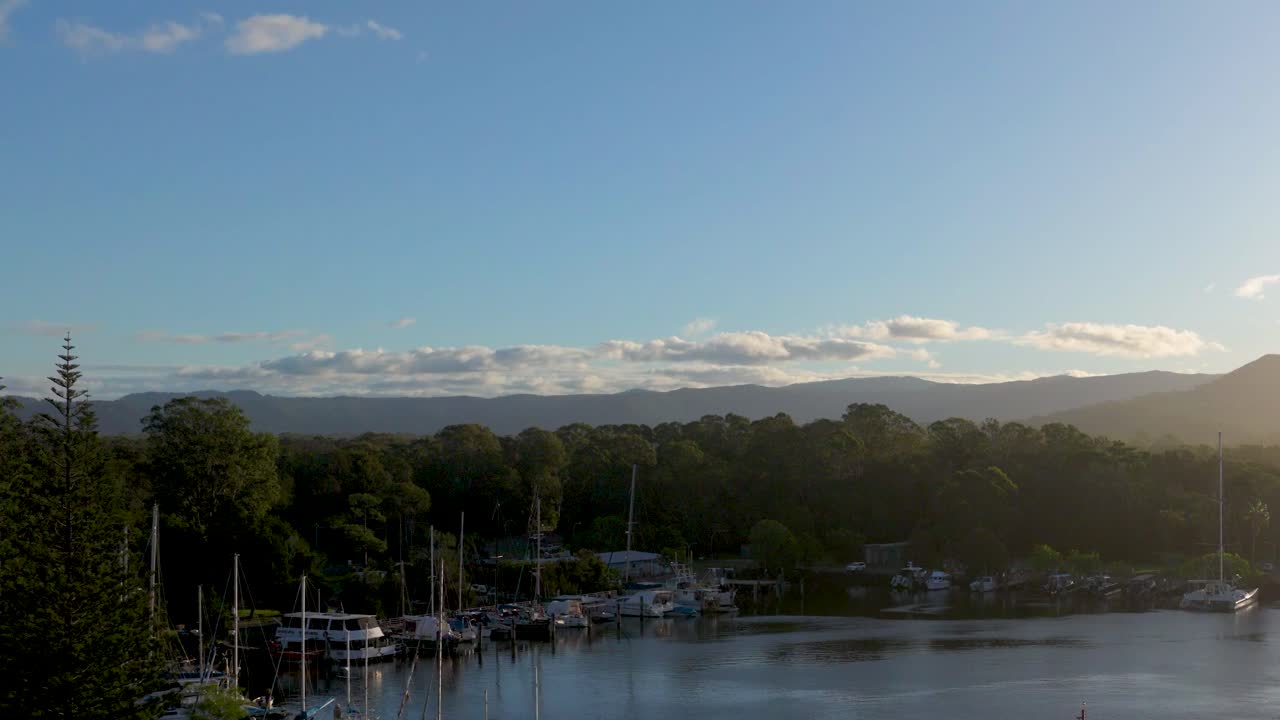 A tranquil sunset view over Brunswick Heads Marina, capturing calm waters and silhouetted trees under a clear sky
