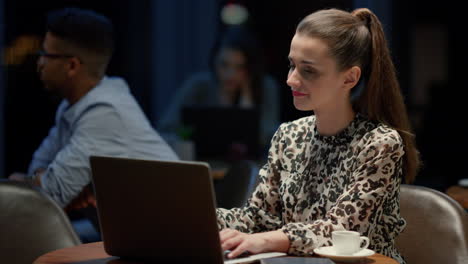 mujer de negocios alegre usando una computadora portátil en un café