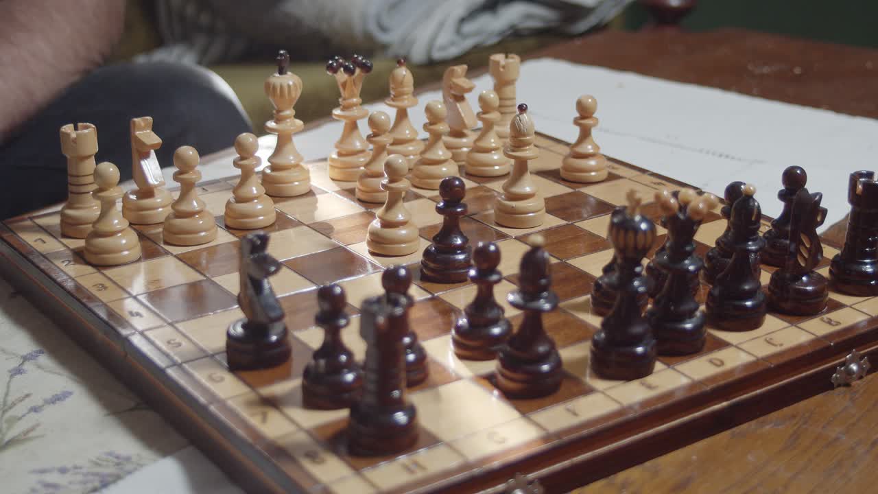 мужчина играет в шахматы на деревянном столе - высокий угол, крупный план