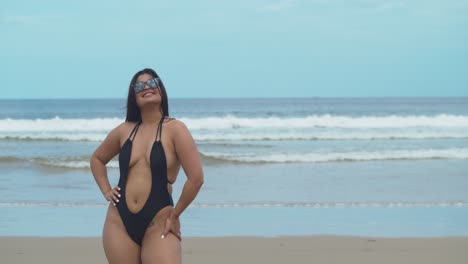 a sexy hispanic girl has her hands on hip and then turns and walks towards the ocean