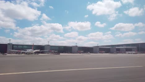 on a partly cloudy daytime, the view from the airplane window captures istanbul airport's terminal building and parked aircraft on the apron