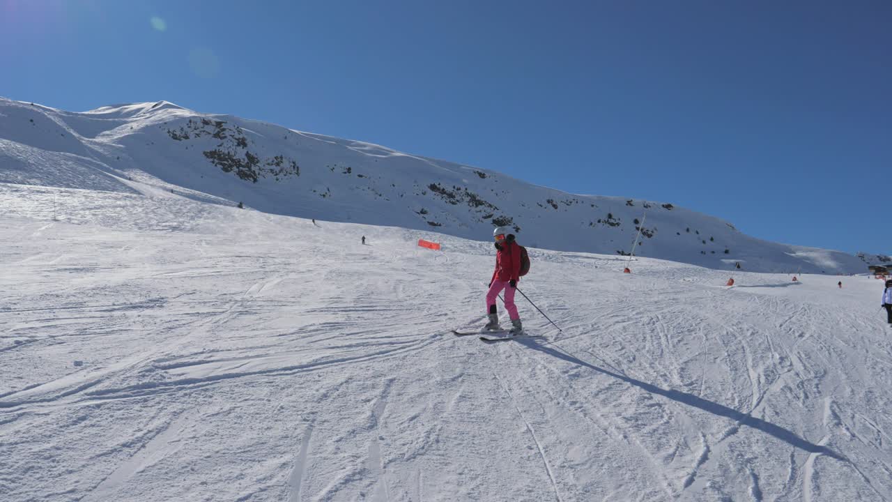 Skier Skiing Down The Ski Slope Along The Mountain In Winter Sunny Day