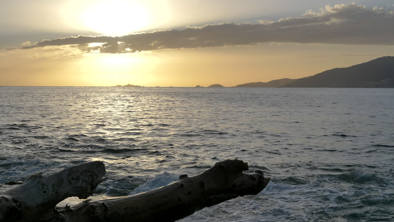 Magnifico tramonto nella baia di Ajaccio, tronco d'albero, legno galleggiante in primo piano SLOMO