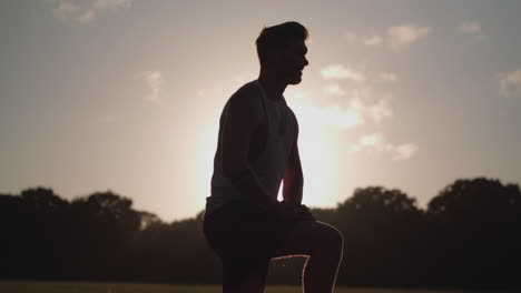 Man-Stretching-His-Legs-Before-a-Run-Whilst-Being-Silhouetted-By-The-Evening-Sun
