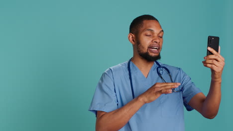 Nurse-waving-hand-in-videocall-meeting-using-phone,-saluting-patient