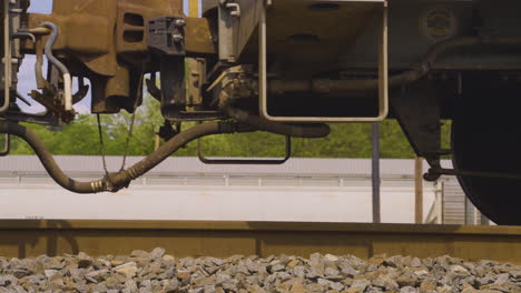 close-up-of-rusty-train-wheels-and-train-car-couplers-as-the-slowly-roll-across-the-railroad-tracks