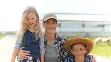 portrait shot of happy cheerful caucasian mother with her son and daughter looking and smiling at camera outside the stable