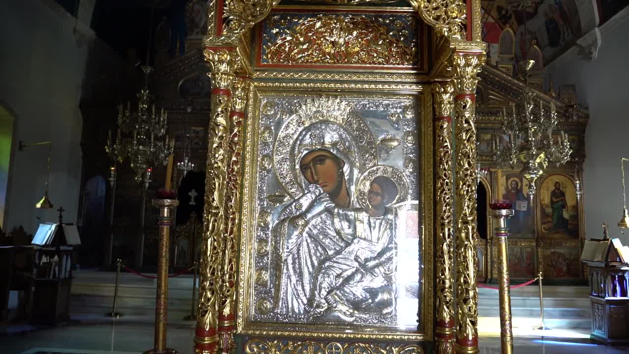 Кинематографический кадр в замедленной съемке внутри большой церкви, с фокусом на иконе Пресвятой Богородицы, с теплым светом, подчеркивающим священные детали и духовную атмосферу