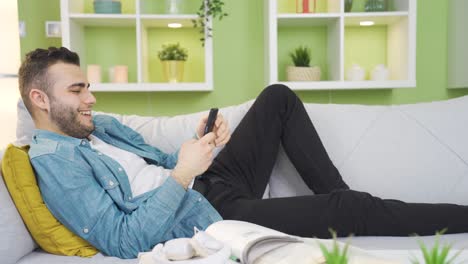 Relaxed-and-happy-young-man-using-phone-at-home.