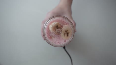 Top-view-of-a-blender-machine-with-sliced-bananas-and-other-fruits-working