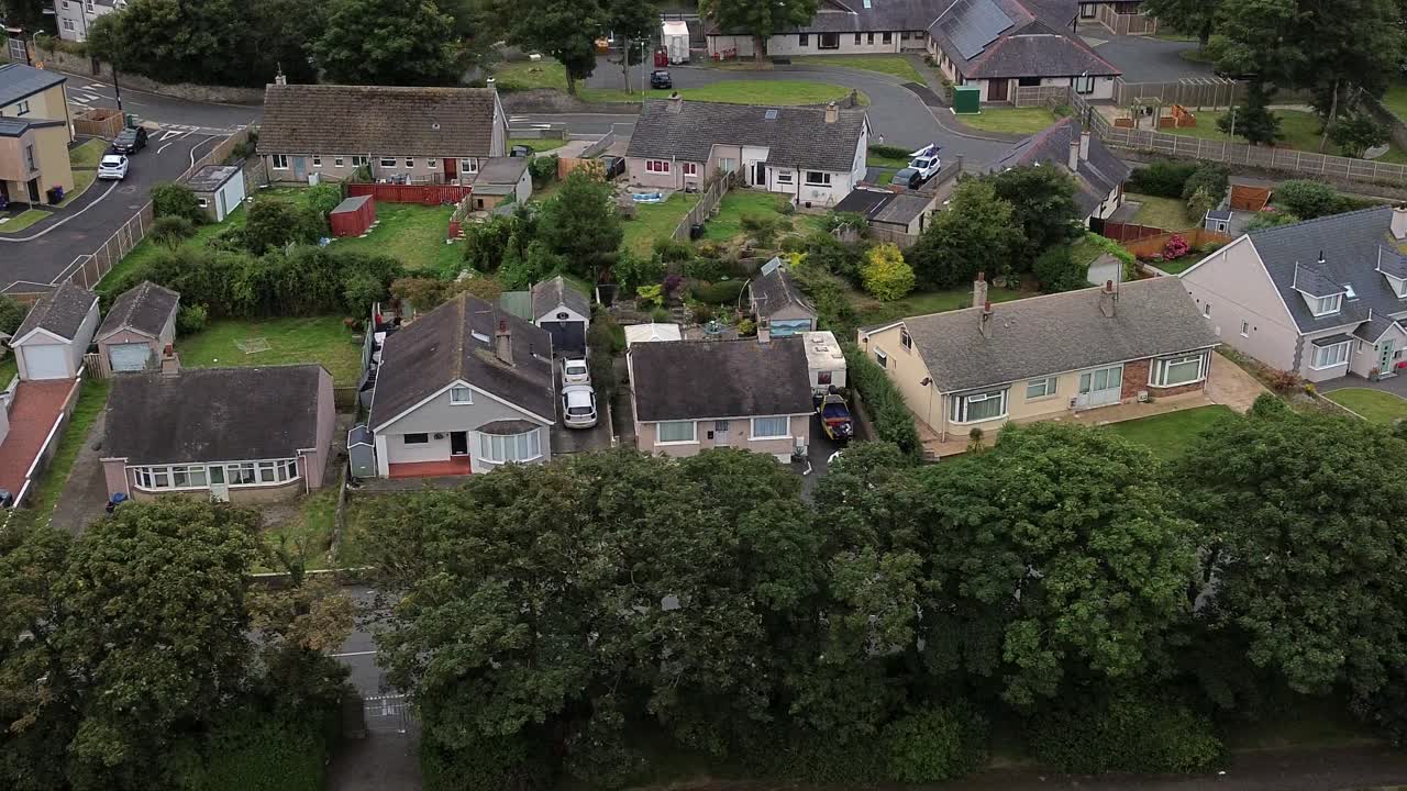 Dronepanorering over forstadshuse i Penrhos, der afslører hustage, haver og tætte træer i et roligt boligområde.