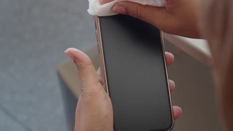 person cleaning smartphone screen with a wipe
