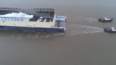 Three-tugboats-pulling-heavy-industrial-barge-with-white-cargo