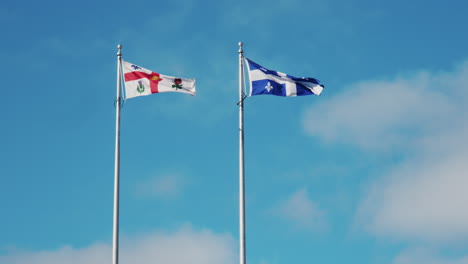 Montreal-and-Quebec-flags-flutter-proudly-side-by-side-against-a-clear-blue-sky-with-wispy-clouds