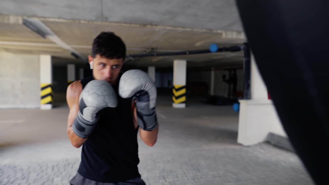 L'uomo sferra colpi potenti al sacco da boxe nella palestra della zona parcheggio