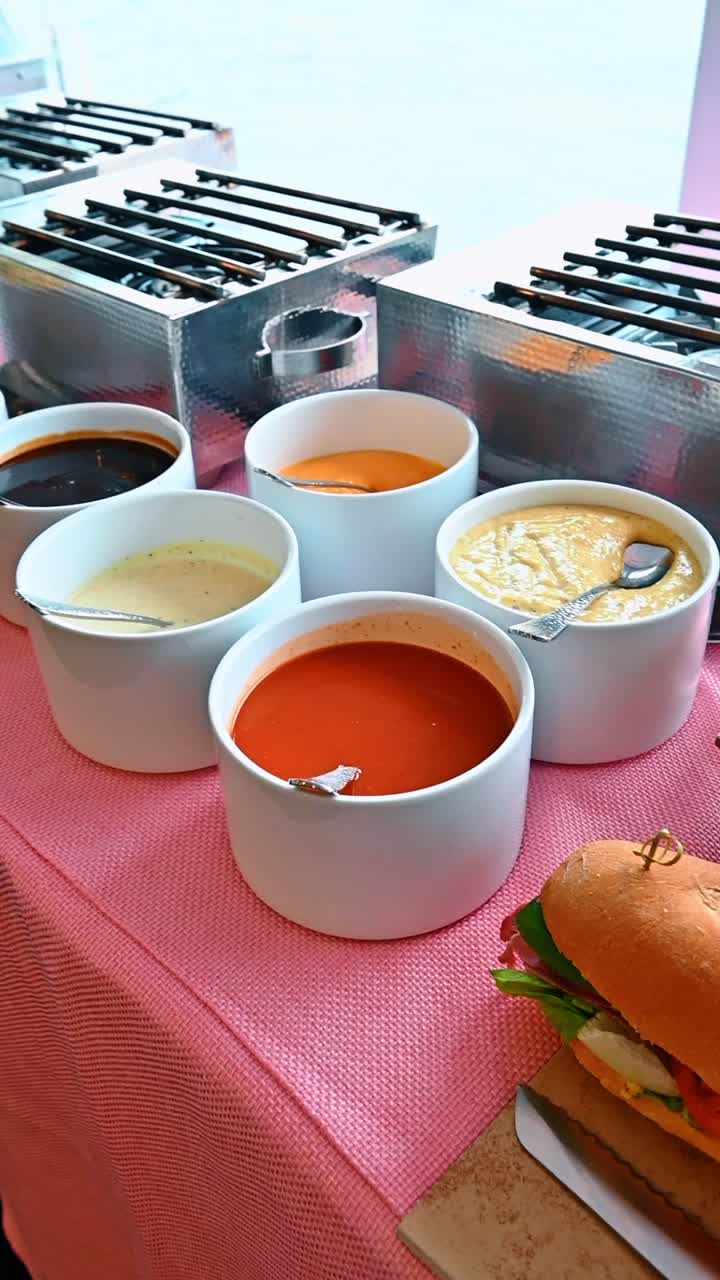 Long baguette submarine sandwiches with vegetables and meat on display. Large stacked baguette sandwiches filled with peppers, greens and cold cuts secured with wooden skewers