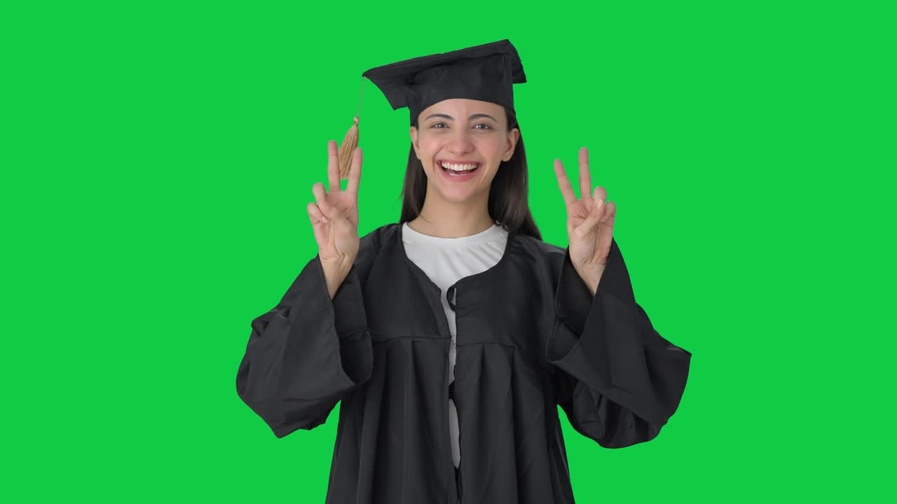 Ragazza indiana laureata felice che mostra il segno della vittoria Green screen