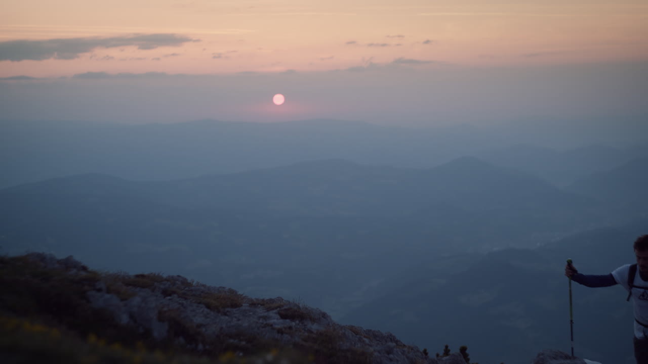 이른 아침에 등산용 기둥과 배낭을 메고 산을 오르는 등산객