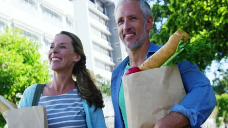 una pareja madura está caminando por la calle con comestibles