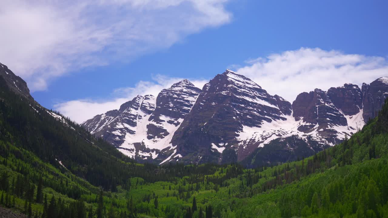 Maroon Lake trail Maroon Bells 14er Wilderness morning sunny blue sky clouds Aspen Snowmass Colorado Elk Range Rocky Mountains White River National Forest melting snow fields pan down motion