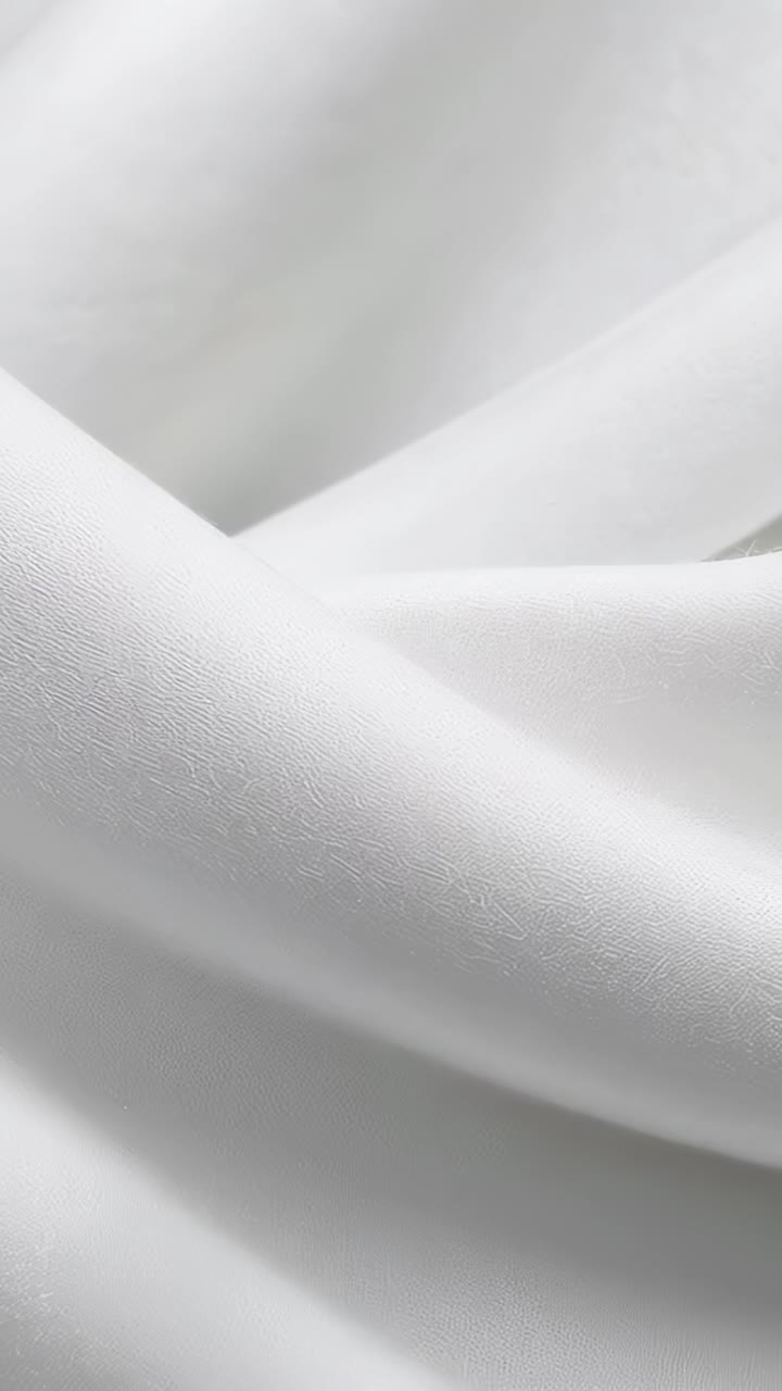 Vertical video: Shifting folded white textile responding to light shift in closeup, showing weave