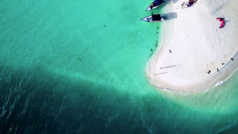 A-person-kayaking-in-the-vibrant-waters-of-playa-madriski,-sunlit-ocean-expanse,-daylight,-aerial-view