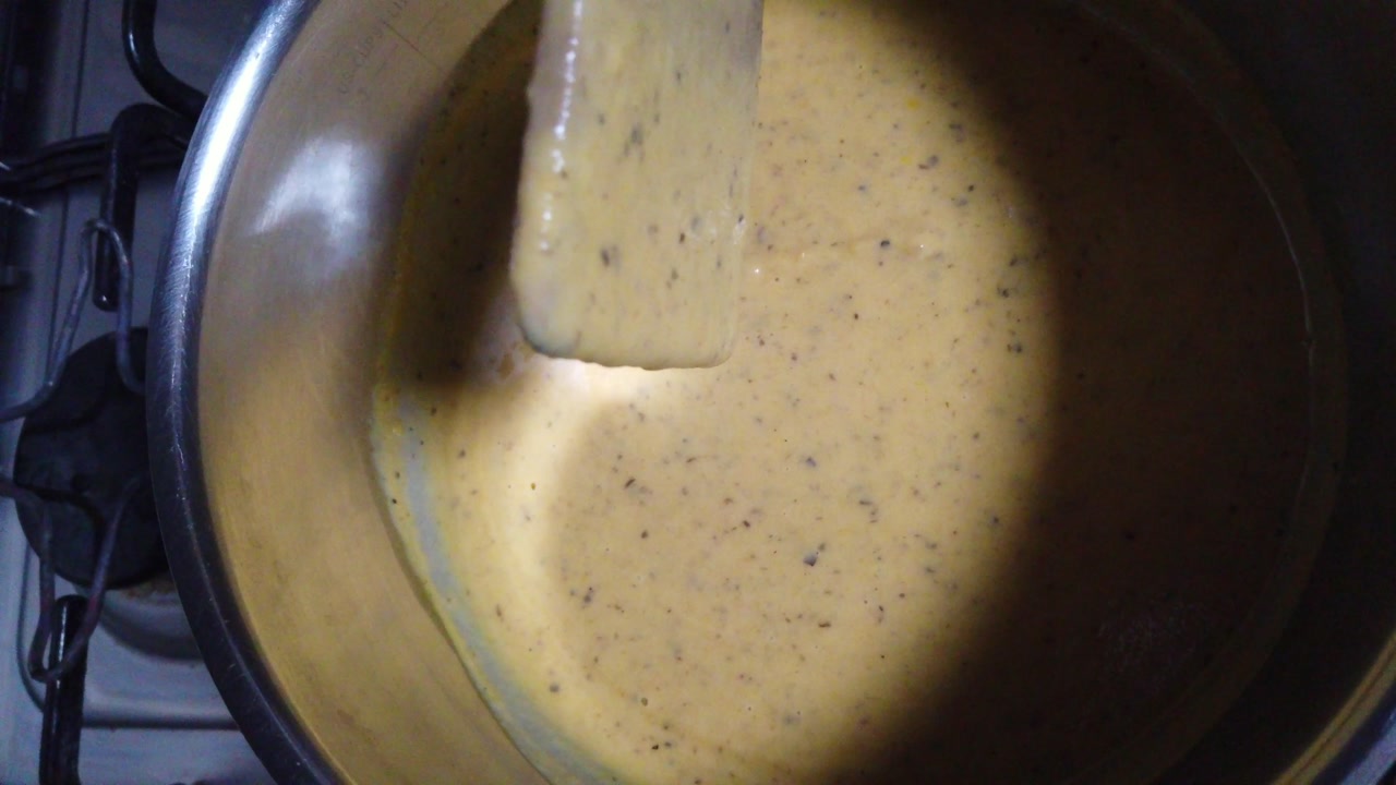 Close-up of pumpkin soup being stirred in a saucepan during the cooking process. Warm and comforting homemade food scene, perfect for recipe videos, cooking tutorials, and healthy lifestyle content.