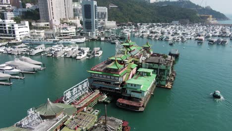 jumbo floating restaurant in hong kong aberdeen harbour typhoon shelter, aerial view with skyscrapers in the background and boats.