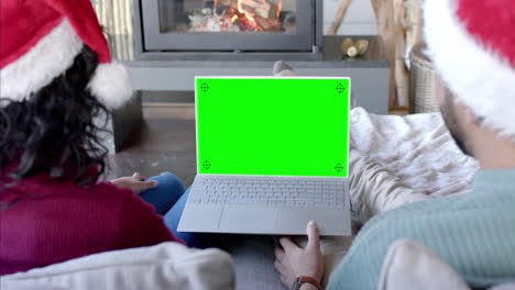 Feliz-Pareja-Diversa-Teniendo-Videollamada-Navideña-Con-Computadora-Portátil-Con-Pantalla-Verde,-Cámara-Lenta