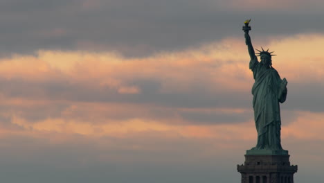 statue of liberty silouetted against pink clouds