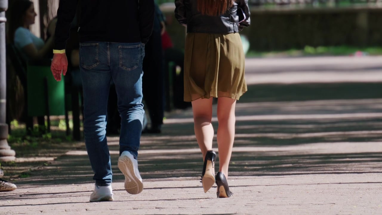 Pareja caminando junta por un sendero soleado en un parque.