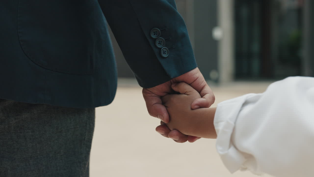A father and child holding hands