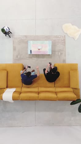 aerial view of friends gaming together on couch. playing video console at home.