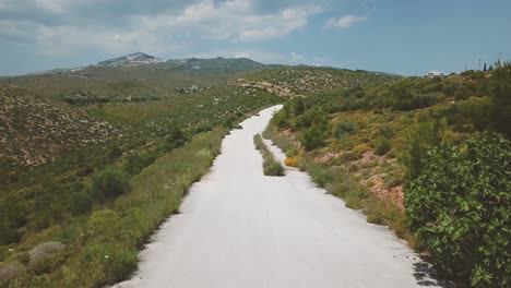 Forward-drone-shot-over-a-motorcyclist-riding-towards-and-passing-under-the-camera-during-a-summer-afternoon