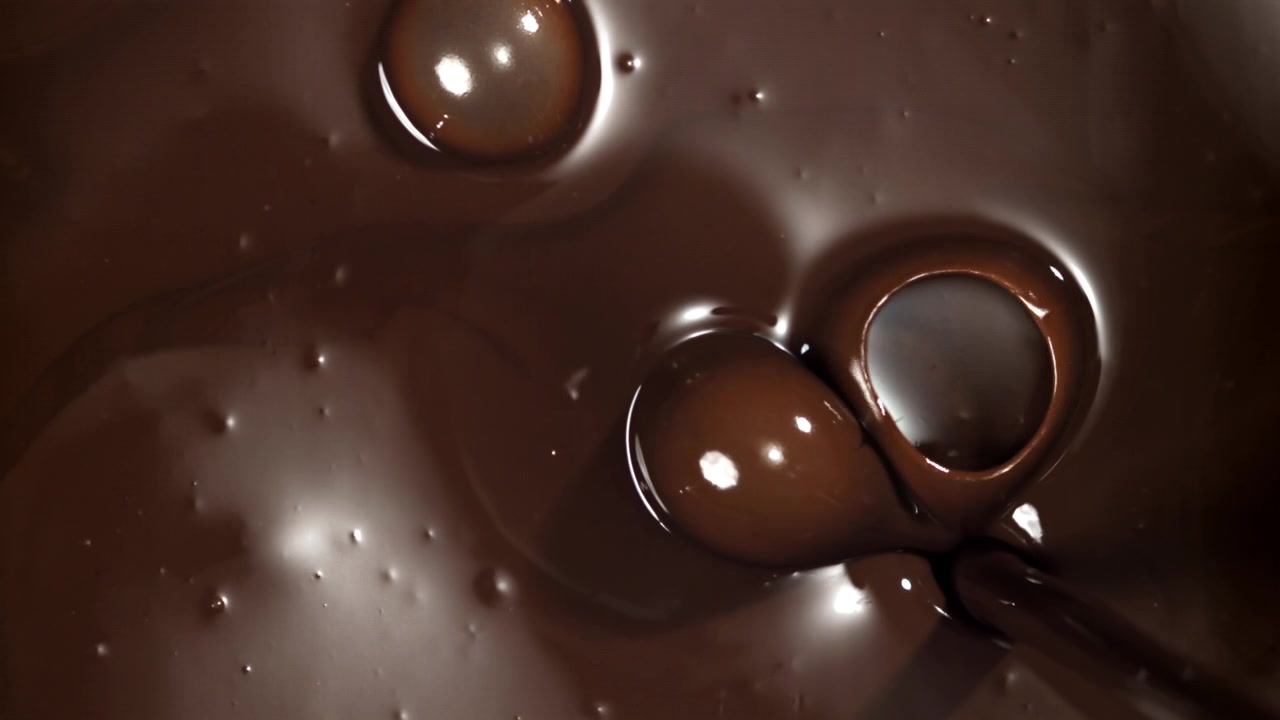 Primo piano al rallentatore di cioccolato fondente fuso che viene versato