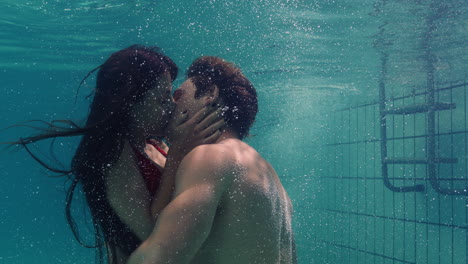 young couple kissing underwater in swimming pool enjoying intimate kiss romantic lovers submerged in water floating with bubbles in passionate intimacy