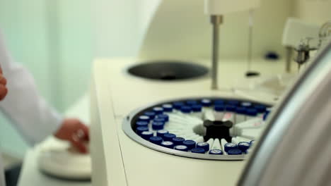 scientist or technician taking blood tubes with bar code put into specimens in chemistry test analysis machine in laboratory centrifuge, hand of a doctor or nurse holds a blood test tube of patients