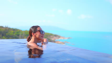 Regla-De-Los-Tercios-Una-Mujer-Joven-Con-La-Altura-Del-Pecho-En-Una-Piscina-Se-Mueve-Hacia-El-Borde-De-La-Piscina-Para-Contemplar-La-Vista-Del-Océano