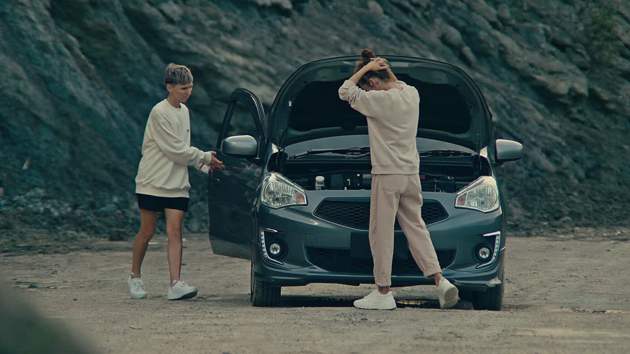 Two women dealing with a broken down car on a remote road