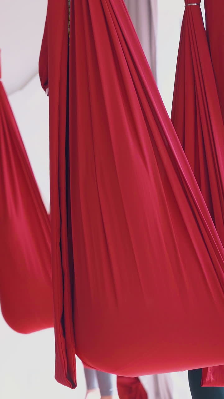 barefoot women legs sitting in oriental fly yoga red hammocks holding fingers in mudra position close view