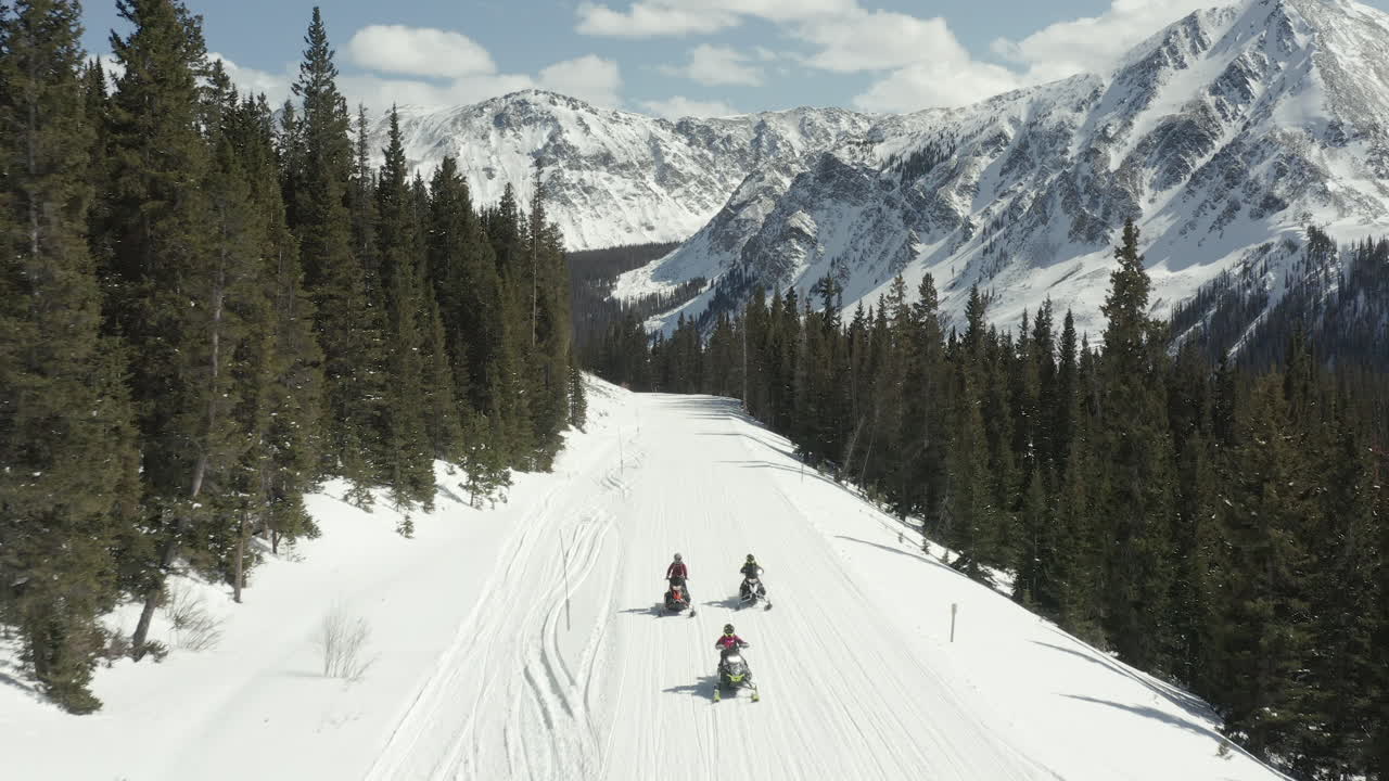 Ripresa con drone di motoslitte che viaggiano sulla neve in montagna.