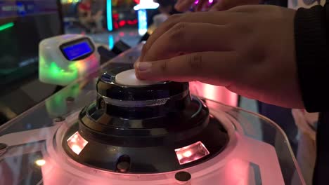 close up hands pressing glowing button of rhythmical music japanese arcade game