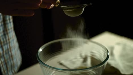 Man-hand-take-sieve-and-sifts-flour-into-glass-bowl.-Powder-flour-in-glass-bowl