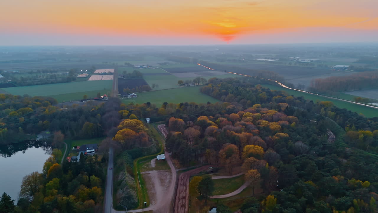 Sunset over Dutch countryside. A peaceful aerial view of the Netherlands features lush fields and trees at sunset