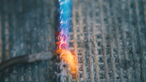 jeweler welds long gold chain on asbestos sheet close view