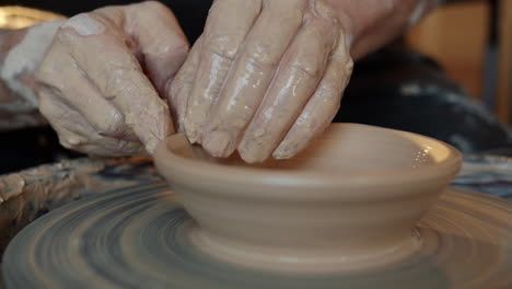 hands shaping a bowl on a pottery wheel