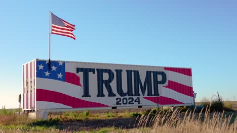 donald trump 2024 presidential election campaign sign with american flag blowing in wind