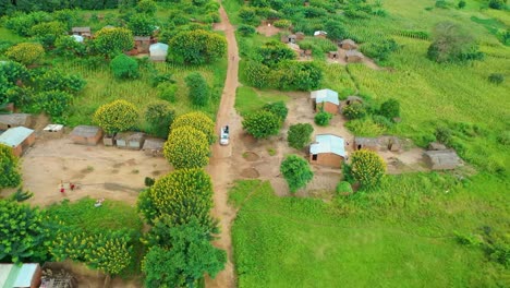 drone flying over a village with a car driving towards it